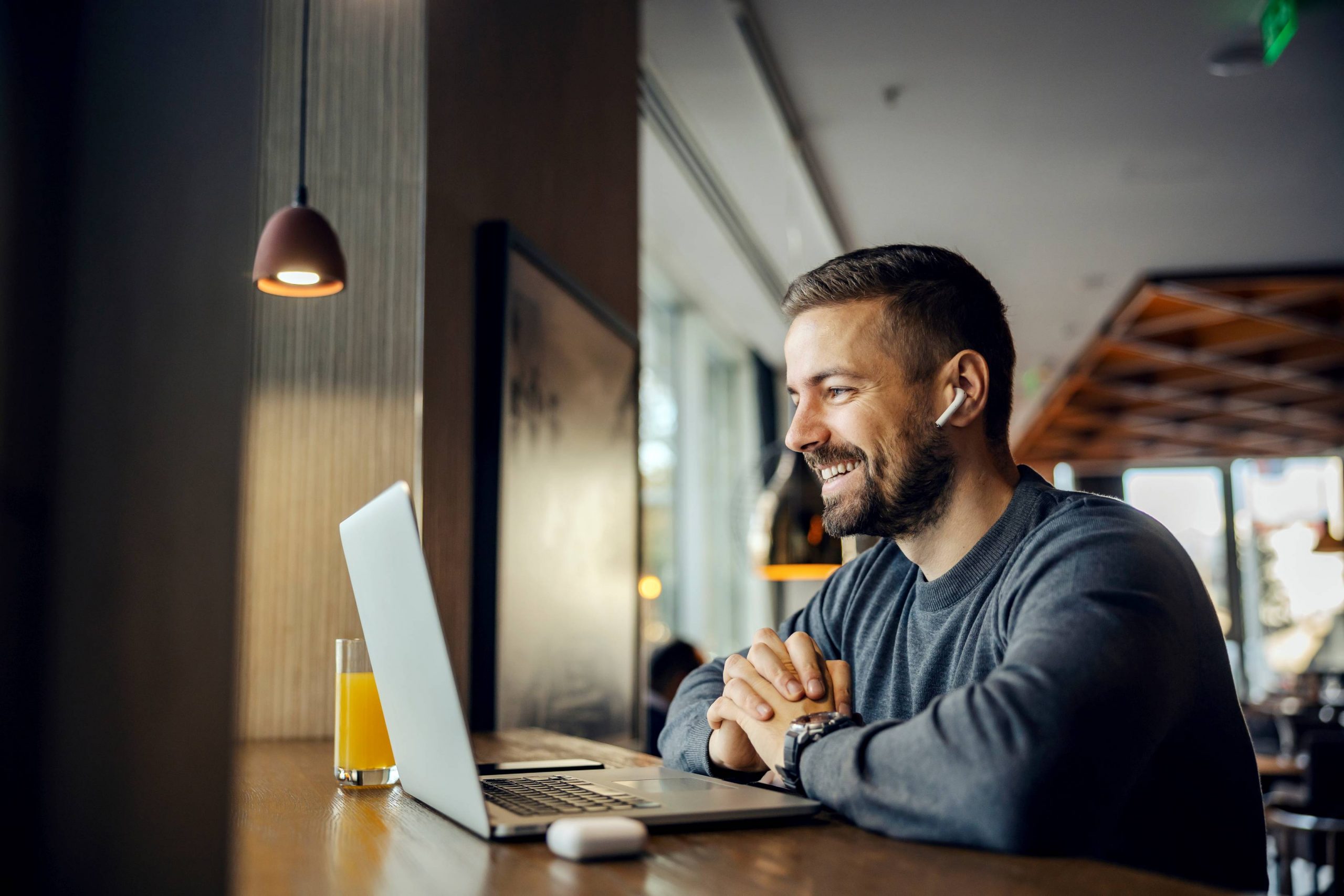 Homme souriant devant un ordinateur portable, évoquant des soins orthodontiques modernes dans un cadre accueillant.