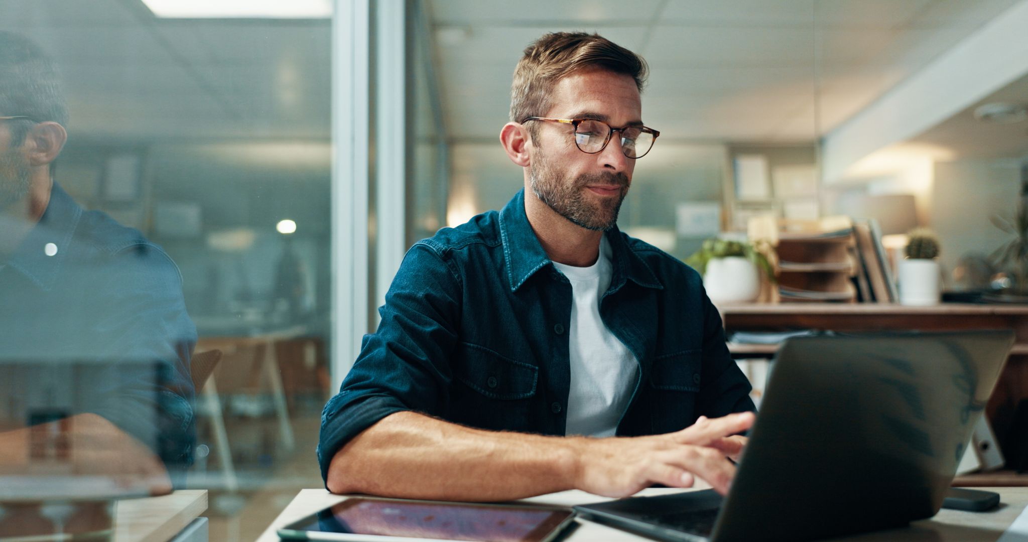 homme en chemise bleue travaillant sur un ordinateur portable dans un cabinet d’orthodontie, représentant des soins modernes et accueillants.