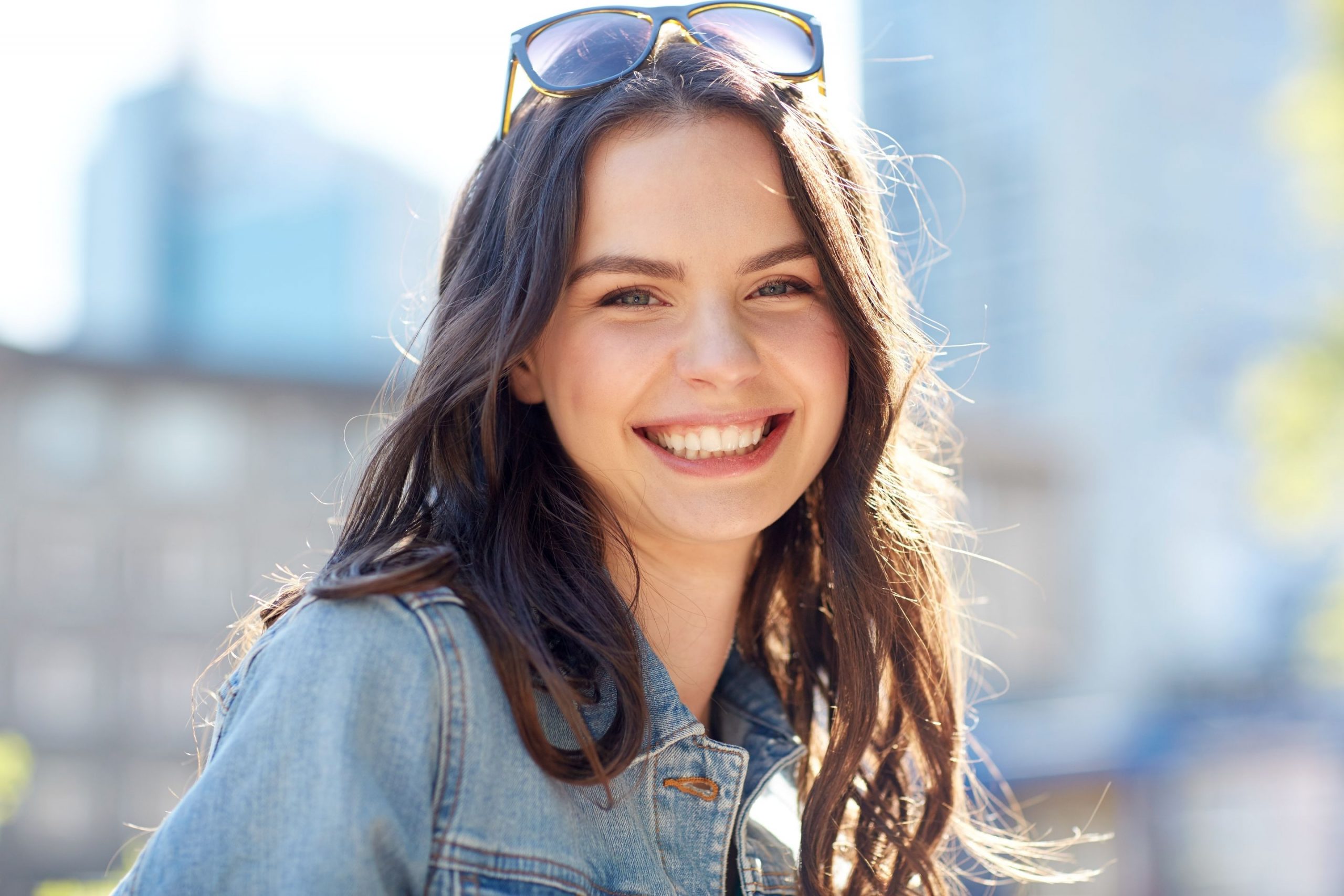 Jeune femme souriante en extérieur, mettant en avant un sourire éclatant, symbole de soins orthodontiques réussis.